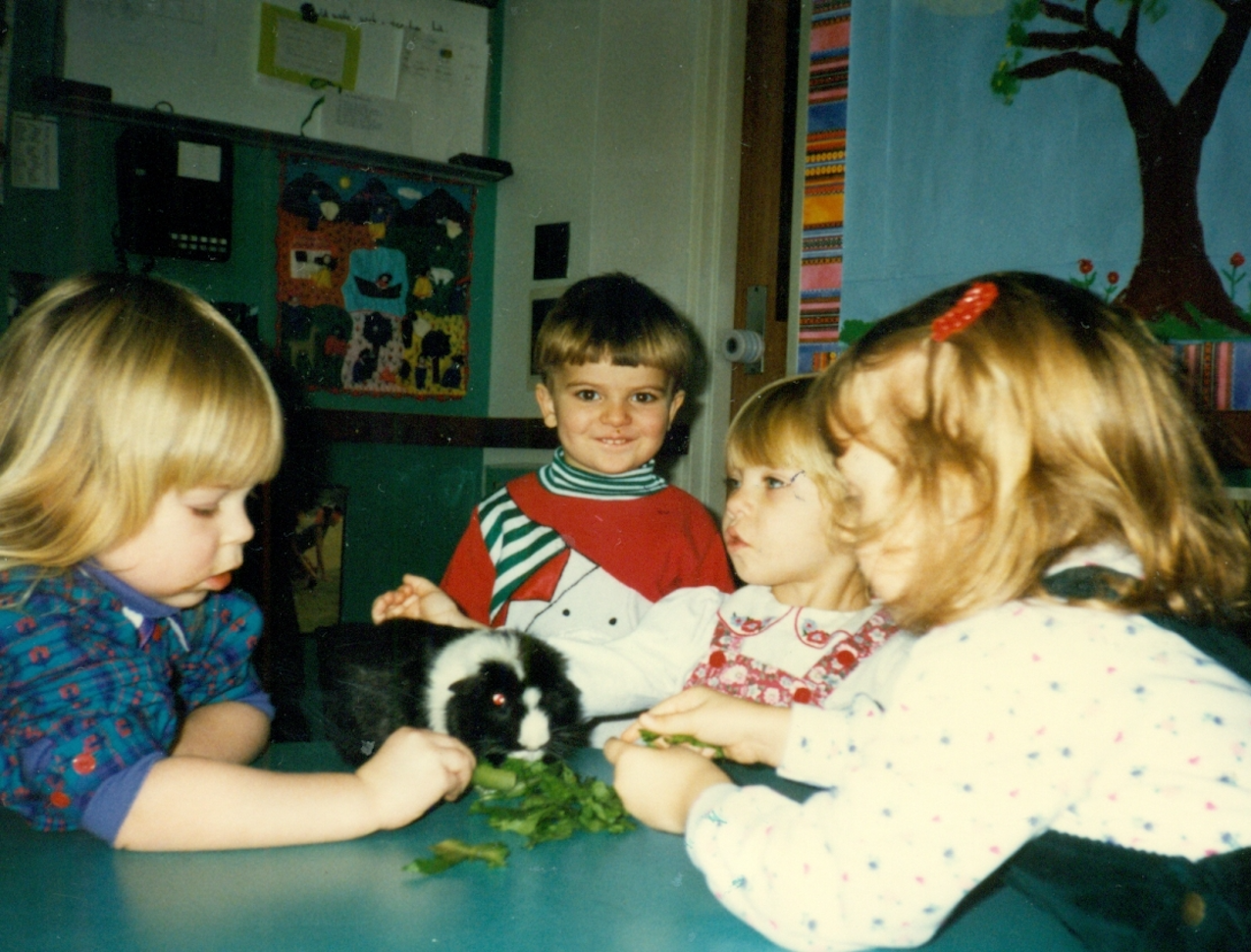 Children around a table feeding a hamster